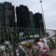 A girl places flowers in front of the fire-damaged residential blocks at Wang Fuk Court. Pic: Reuters
