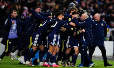 Kieran Tierney is mobbed by the Scotland bench after giving them a late 3-2 lead over Denmark