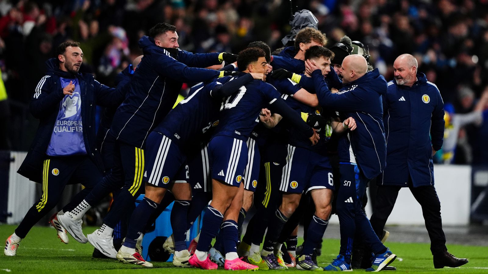 Kieran Tierney is mobbed by the Scotland bench after giving them a late 3-2 lead over Denmark
