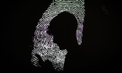 A silhouette of a boy looking at his phone on a enlarged thumbprint background