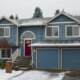 blue suburban-style house with snow covering the yard and driveway