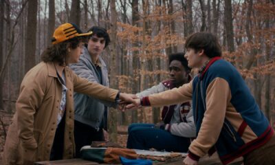 Dustin, Mike, Lucas, and Will putting their hands out and on top of each other&#039;s in Stranger Things season 5