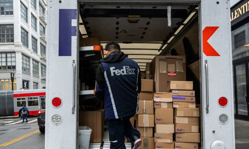 A worker unloading packages from a FedEx truck.