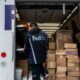 A worker unloading packages from a FedEx truck.