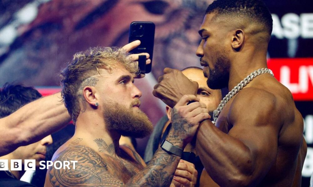 Jake Paul grabs Anthony Joshua's fist during a face-off