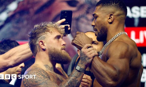 Jake Paul grabs Anthony Joshua's fist during a face-off