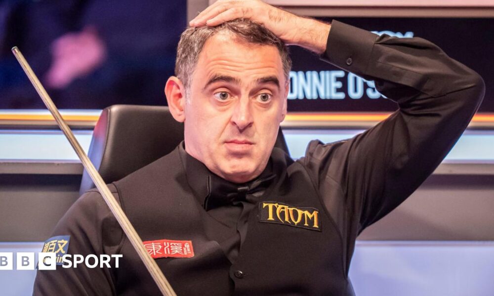 Ronnie O'Sullivan puts his left hand on his head as he watches play from his seat