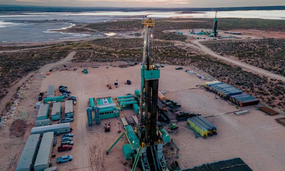 Drone captures a breathtaking sunset over the Permian Basin, showcasing an oil rig drilling and fracking for oil, amidst the vastness of the landscape