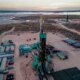 Drone captures a breathtaking sunset over the Permian Basin, showcasing an oil rig drilling and fracking for oil, amidst the vastness of the landscape