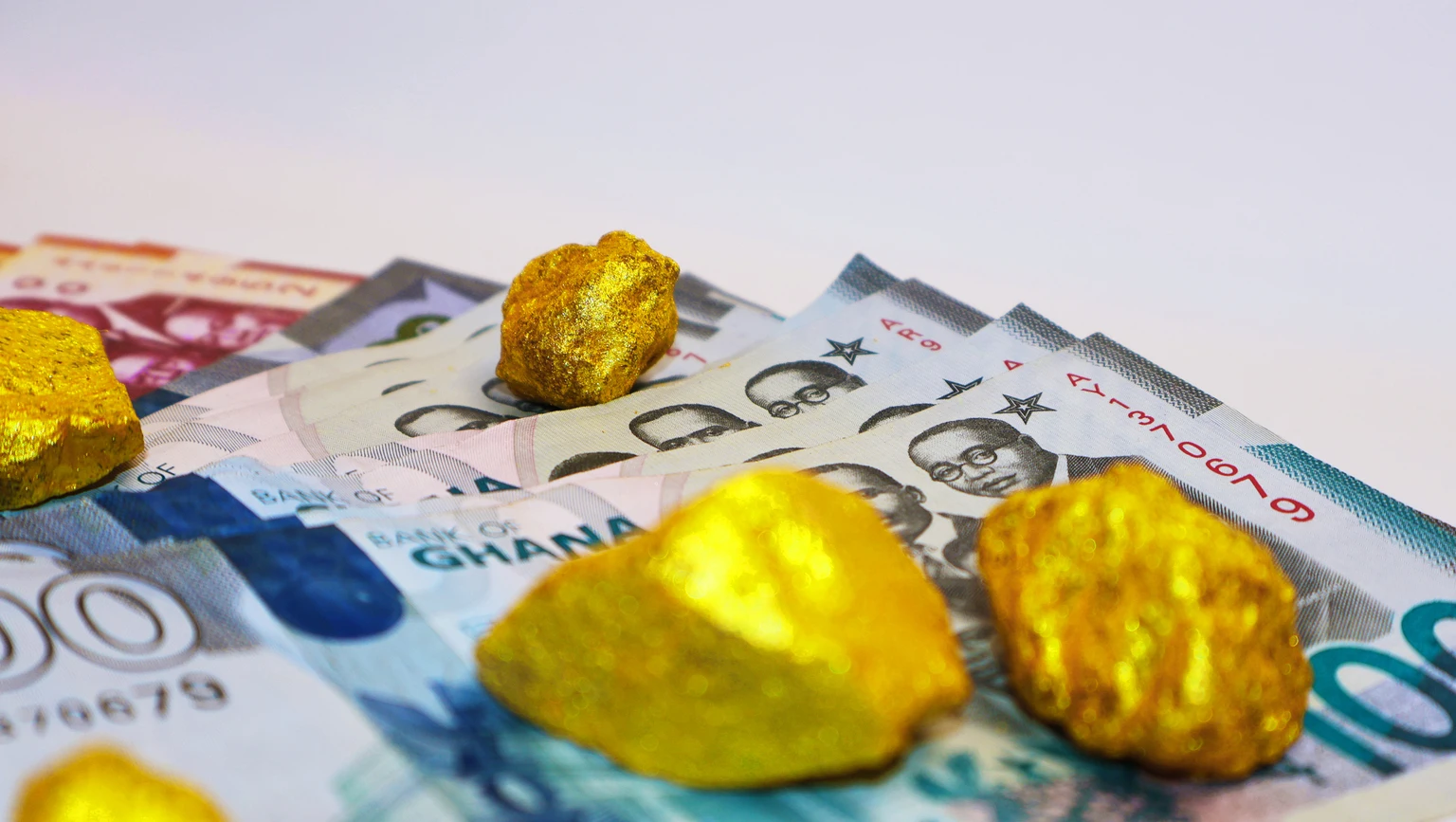 Ghanaian cedi notes and Lump of pure Gold on white background. Raw golden metal ore, galamsey minning wealthy rich precious mineral