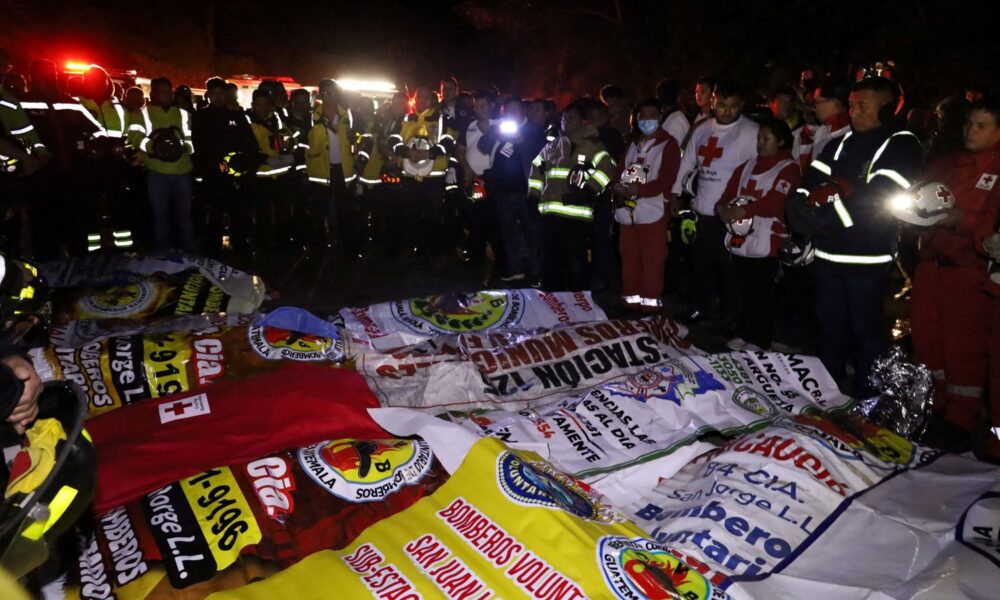 Paramedics and firefighters stand next to the covered bodies of victims. Pic: Reuters