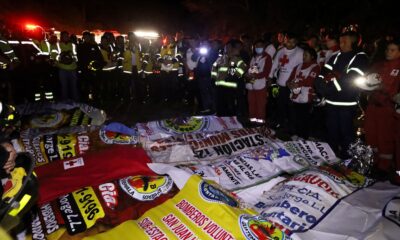 Paramedics and firefighters stand next to the covered bodies of victims. Pic: Reuters
