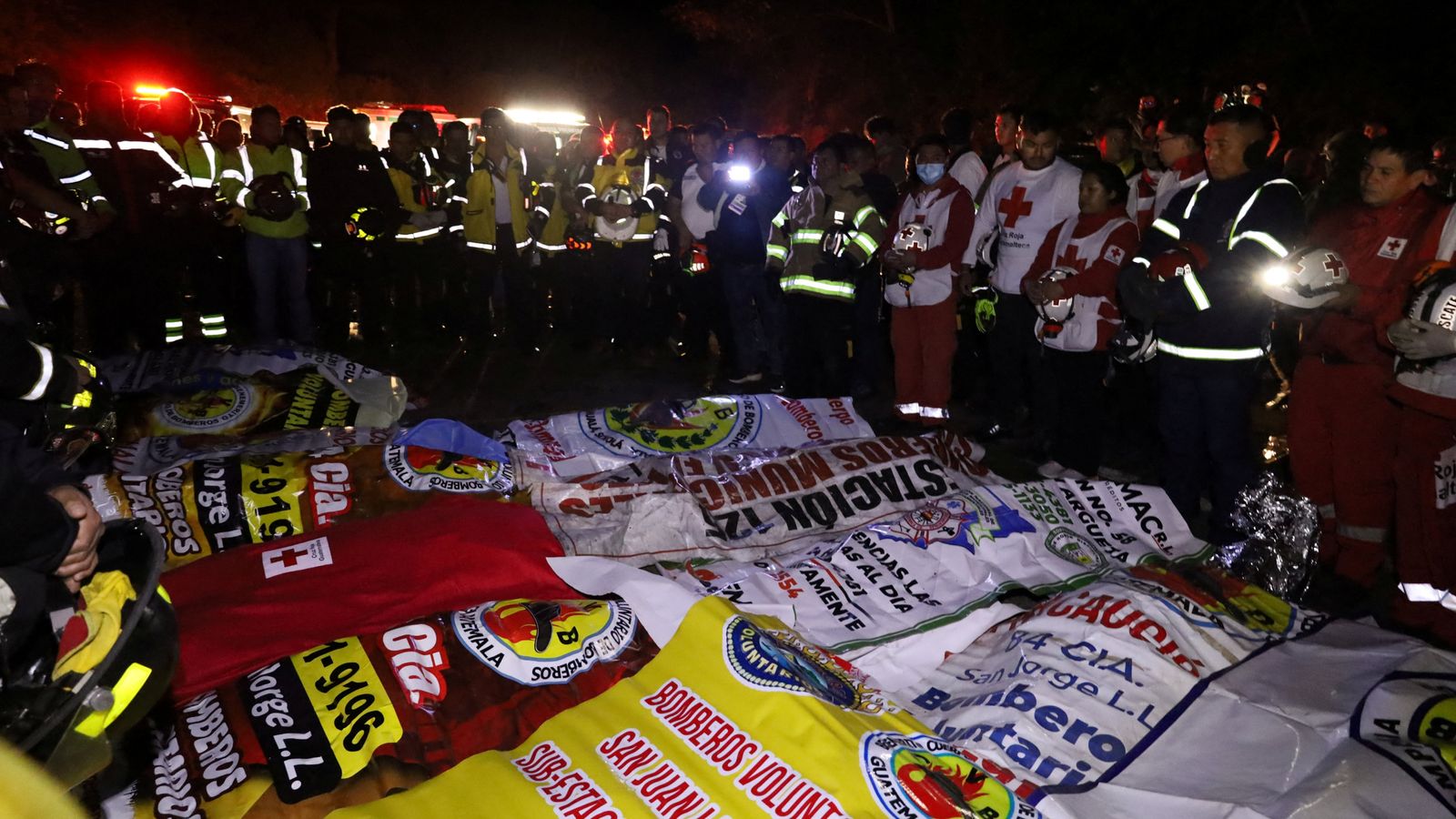 Paramedics and firefighters stand next to the covered bodies of victims. Pic: Reuters