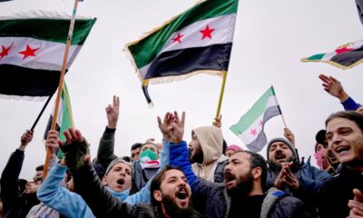 Syrians in Damascus await a parade by the new Syrian army marking a year since the ousting of Bashar Assad. Pic: AP