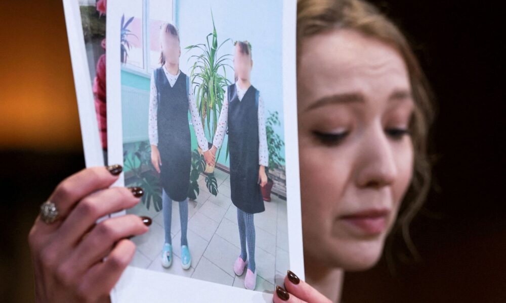 Kateryna Rashevska holding pictures said to show abducted Ukrainian children at the US Capitol last week. Pic: Reuters