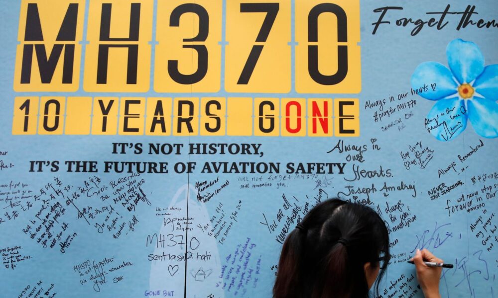 A woman writes a message on a board during last year's 10th annual remembrance event for missing flight MH370. Pic: AP