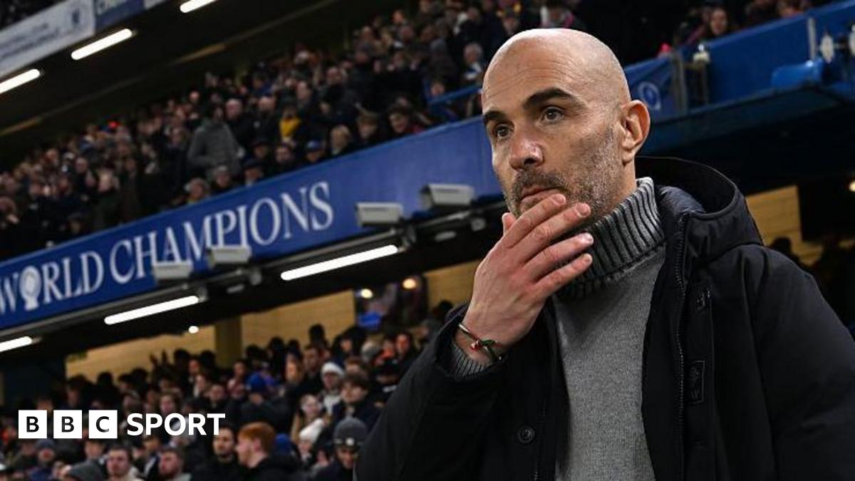 Enzo Maresca, manager of Chelsea, looks on prior to the Premier League match between Chelsea and Bournemouth at Stamford Bridge. He is wearing a grey jumper beneath a dark coat.