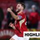 Luke Garbutt celebrates with fist in the air in red Salford City kit