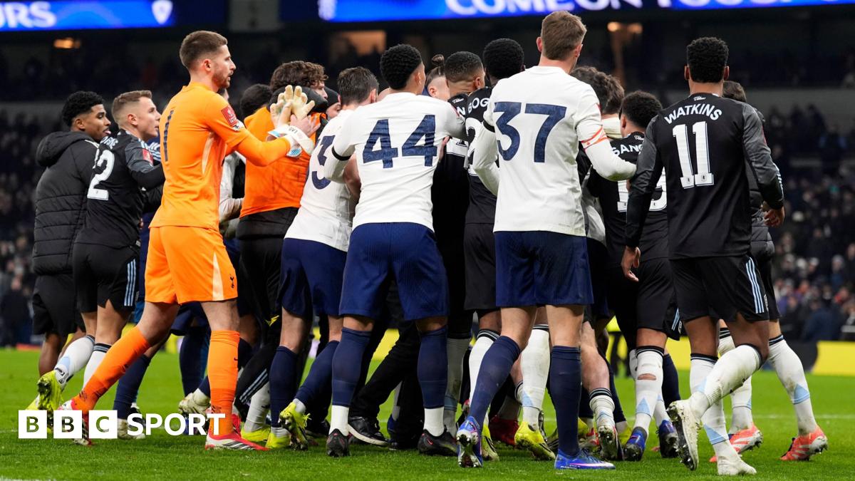 Tottenham Hotspur and Aston Villa players swarm in a melee after their FA Cup match, with the crowd in the distant background