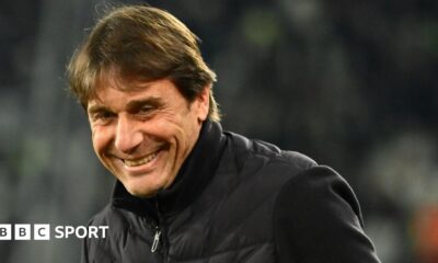 Head and shoulders view of a smiling Antonio Conte in a black, zipped-up jacket