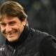 Head and shoulders view of a smiling Antonio Conte in a black, zipped-up jacket