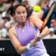 Daria Kasatkina, in a lilac tennis vest, plays a two-handed backhand shot as her eyes suggest intense focus