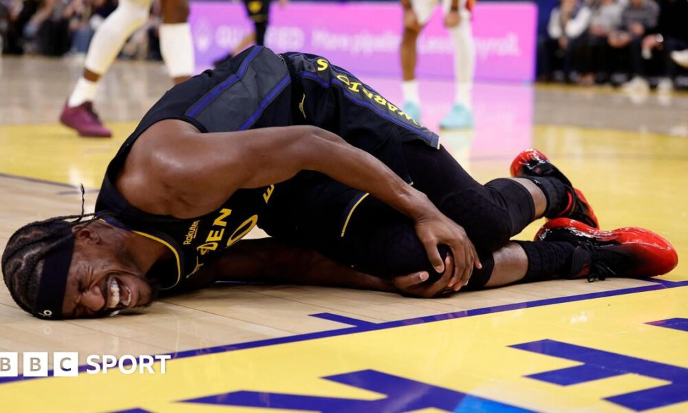 Golden State Warriors forward Jimmy Butler lies on the floor in agony, holding his right knee after tearing his ACL