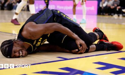Golden State Warriors forward Jimmy Butler lies on the floor in agony, holding his right knee after tearing his ACL
