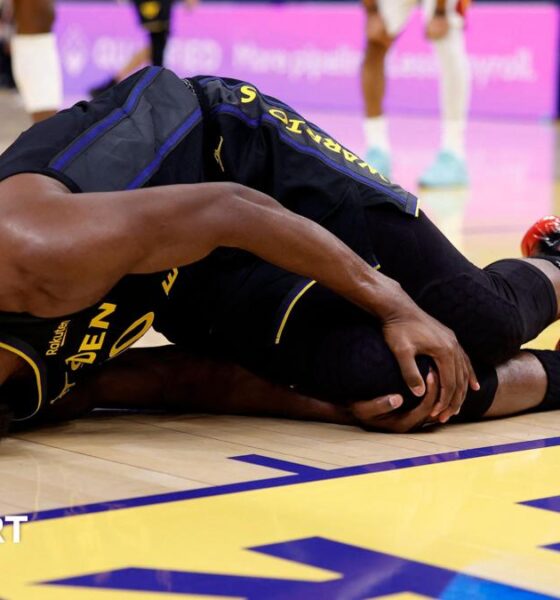 Golden State Warriors forward Jimmy Butler lies on the floor in agony, holding his right knee after tearing his ACL