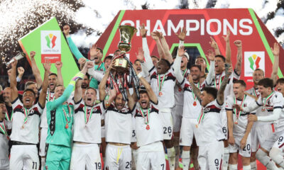 ROME, ITALY - MAY 14: Lewis Ferguson, Lorenzo De Silvestri and Riccardo Orsolini of Bologna lift the Coppa Italia trophy as their team mates celebrate after the team's victory in the Coppa Italia Final match between AC Milan and Bologna at Stadio Olimpico on May 14, 2025 in Rome, Italy. (Photo by Paolo Bruno/Getty Images)