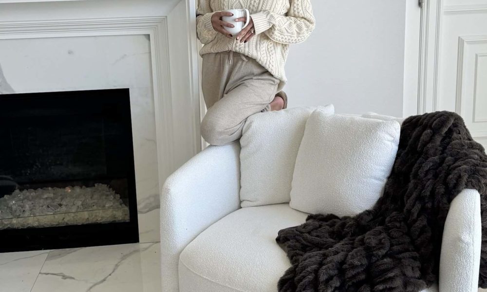 Christine Andrew at home in her primary bedroom with her white accent swivel chair.