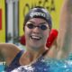 Swimmer Emily Barclay smiles and waves after a race