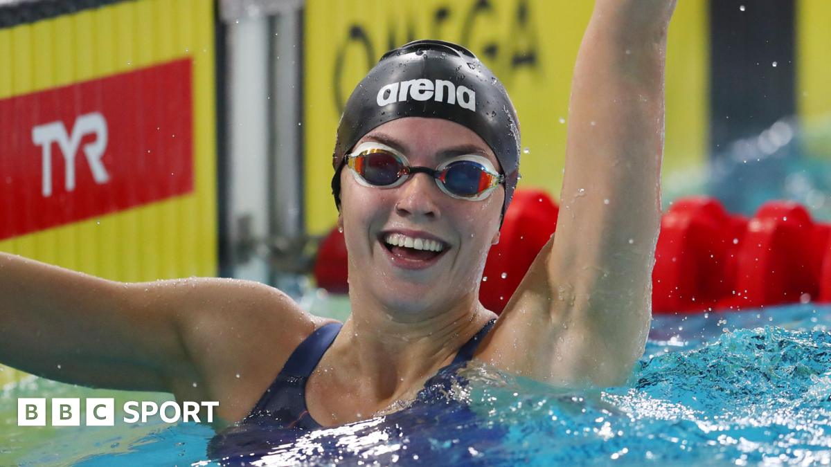 Swimmer Emily Barclay smiles and waves after a race