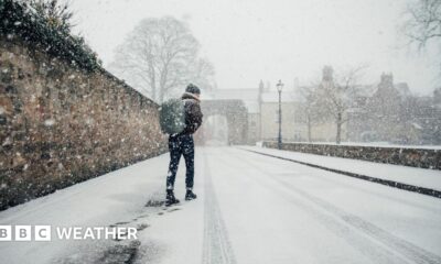 Man walks along a snow covered street with a rucksack on his back