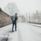 Man walks along a snow covered street with a rucksack on his back