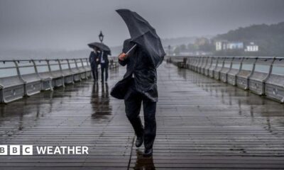 man holding an umbrella trying to shelter from heavy rain and breezy weather