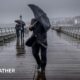 man holding an umbrella trying to shelter from heavy rain and breezy weather