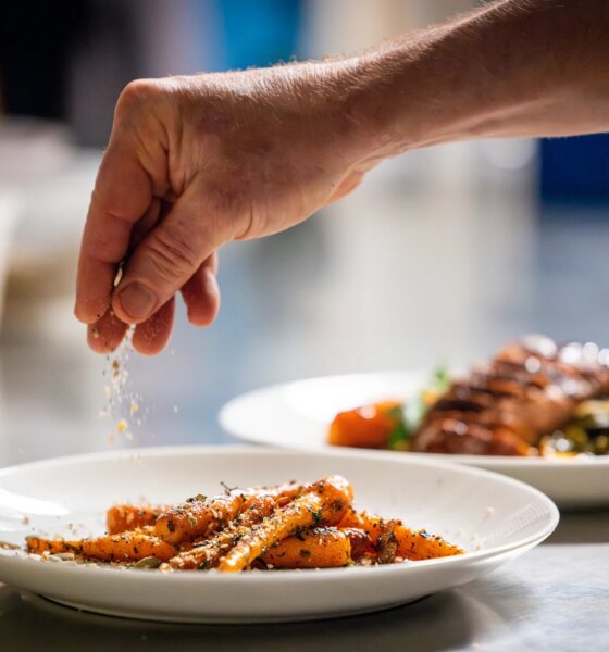 A hand puts the finishing touches on a plate of delicious carrots