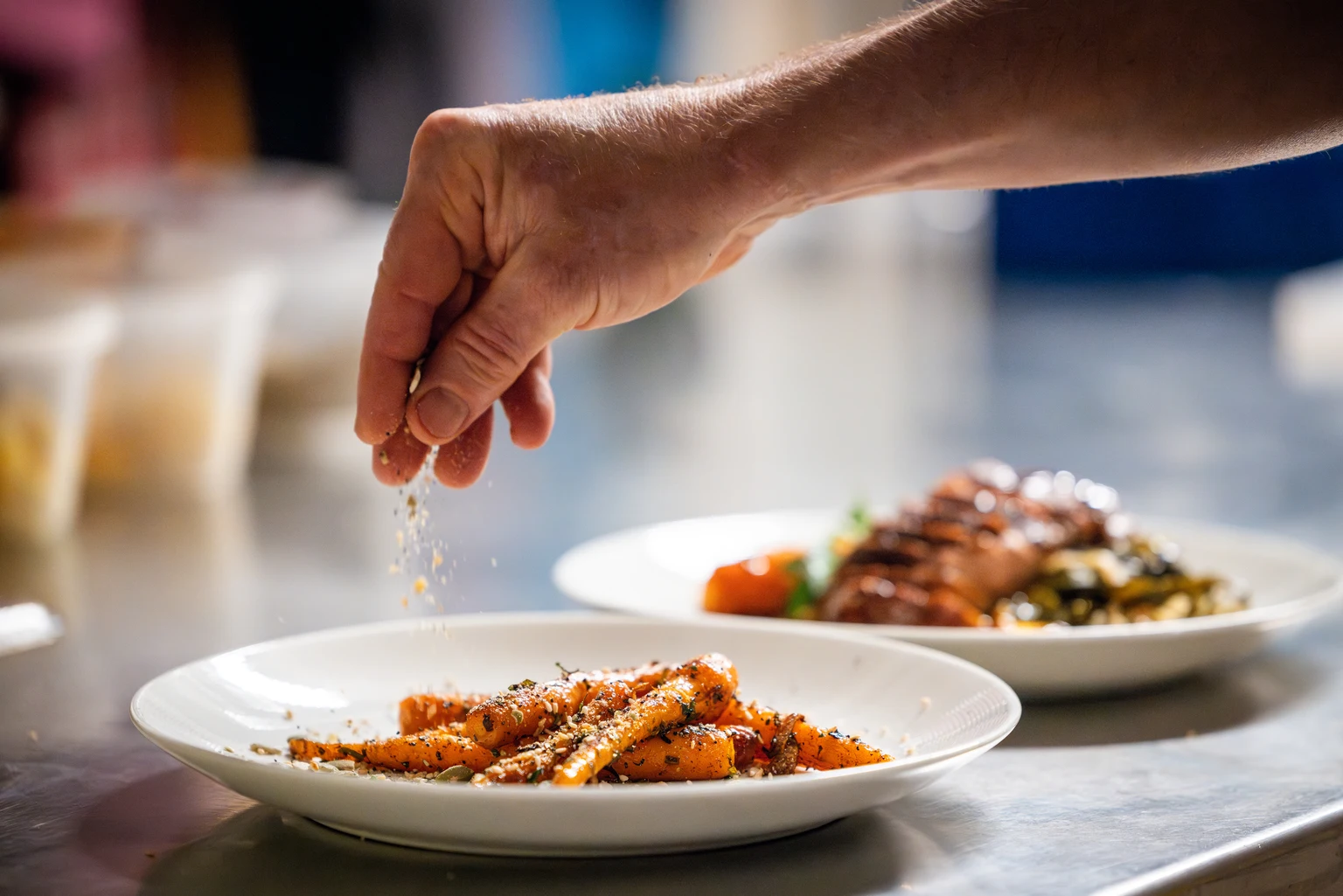 A hand puts the finishing touches on a plate of delicious carrots
