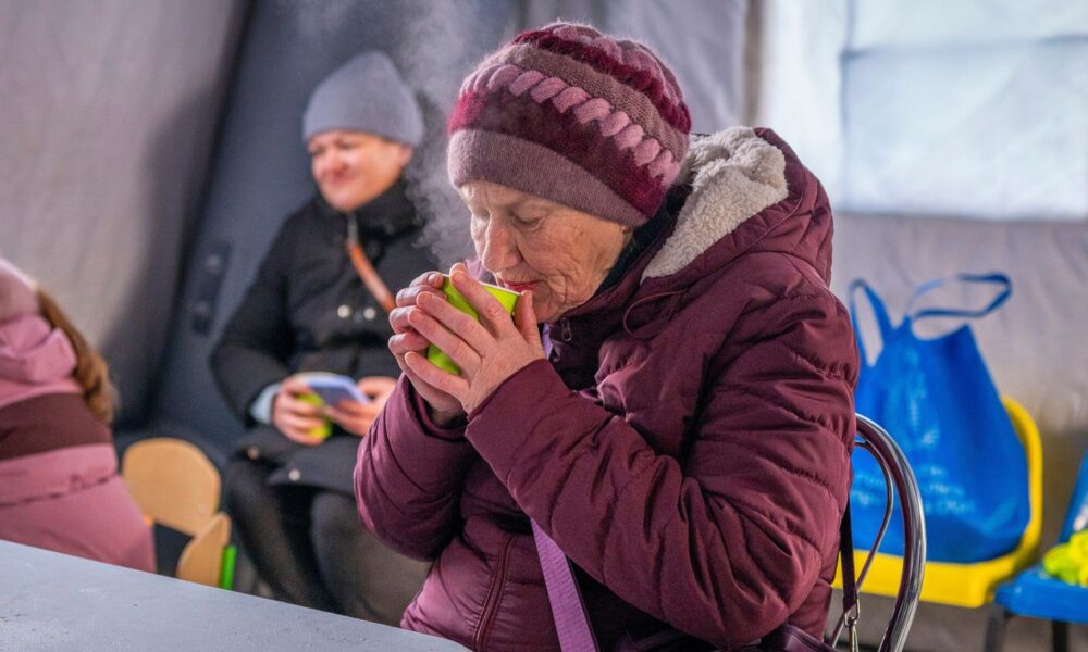 A woman gets warm at an emergency center set up to support people during power outages in Boryspil. Pic: AP