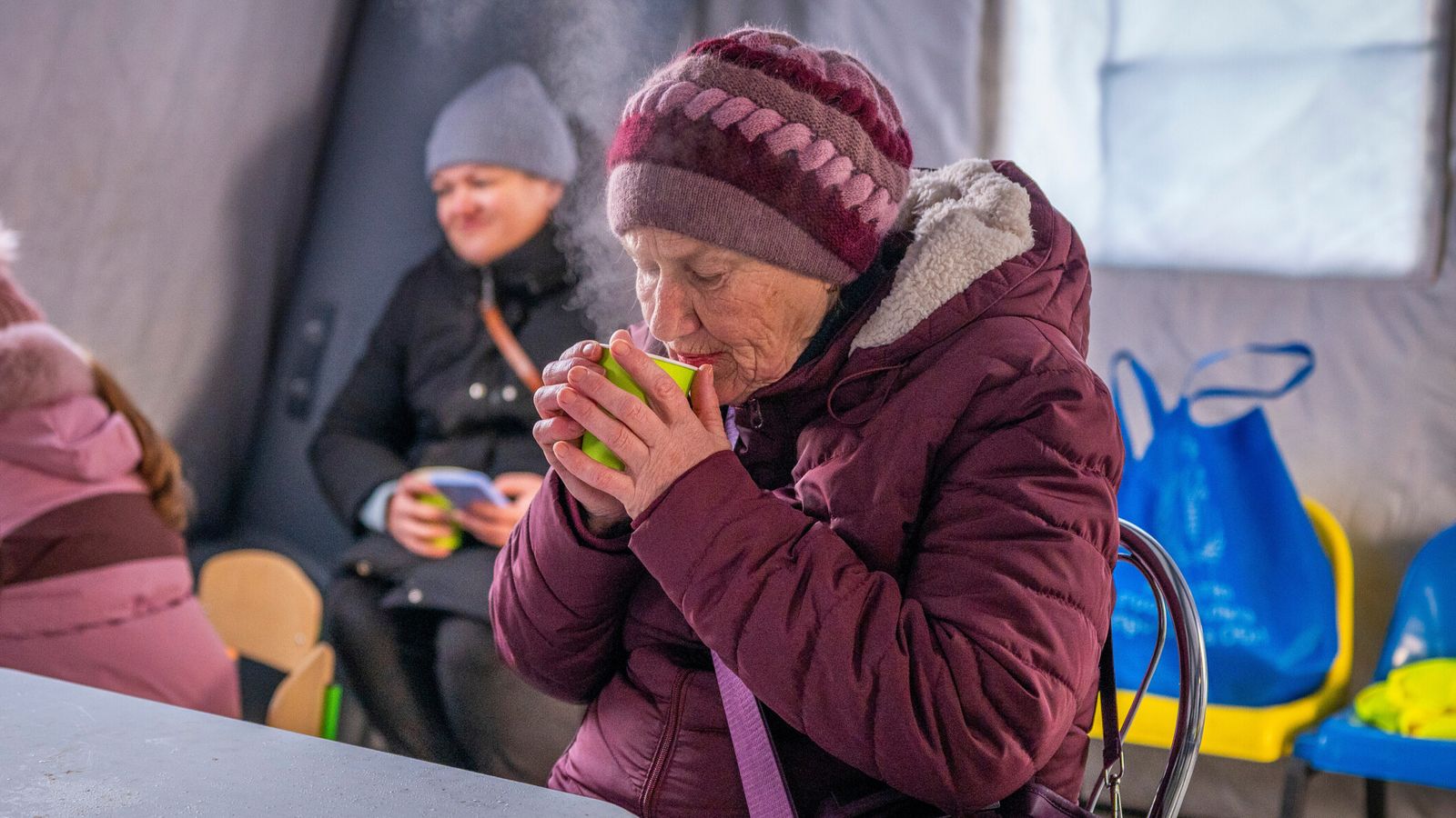 A woman gets warm at an emergency center set up to support people during power outages in Boryspil. Pic: AP