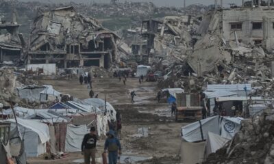 Palestinians seen earlier this week walking amid buildings destroyed by Israeli air and ground operations in Gaza. Pic: AP