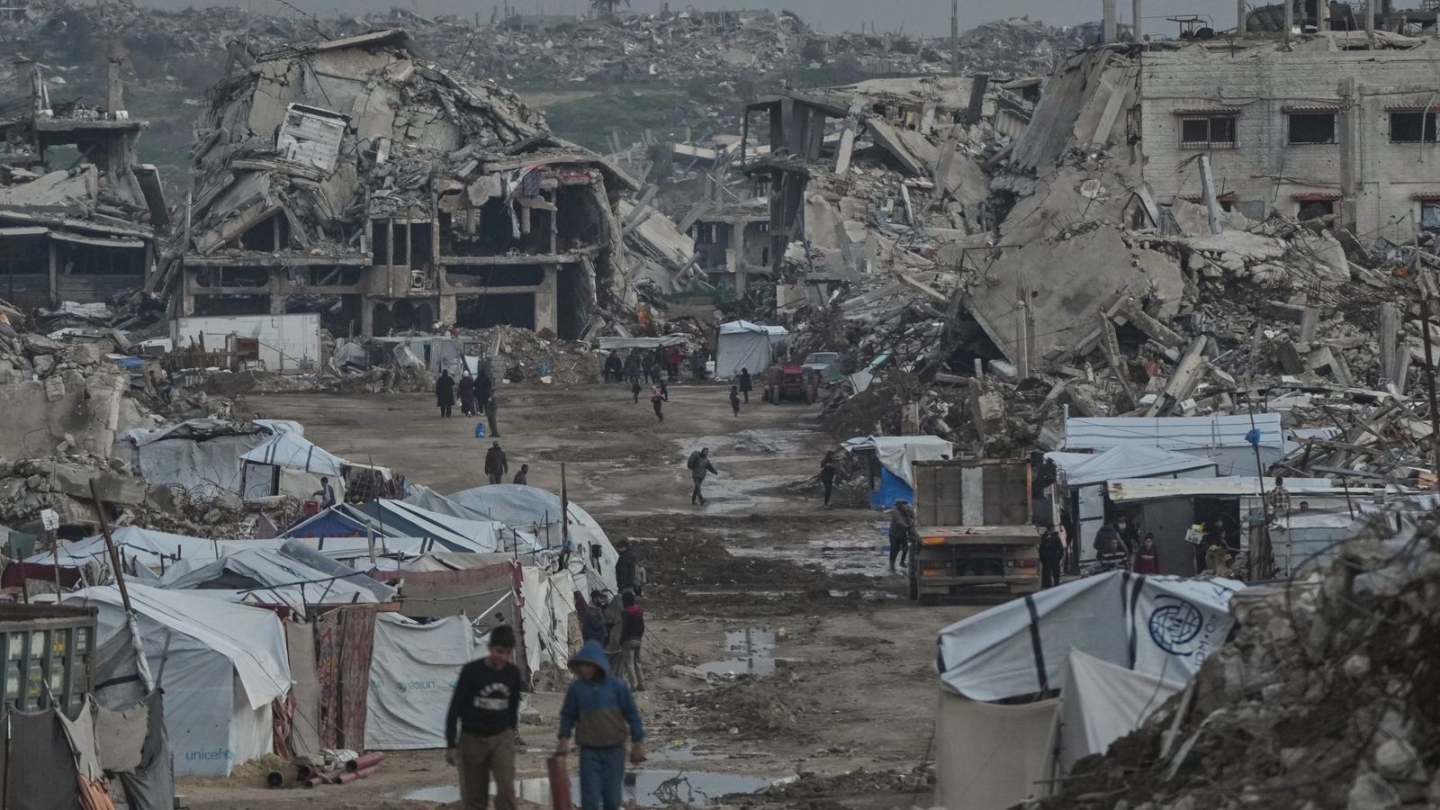 Palestinians seen earlier this week walking amid buildings destroyed by Israeli air and ground operations in Gaza. Pic: AP