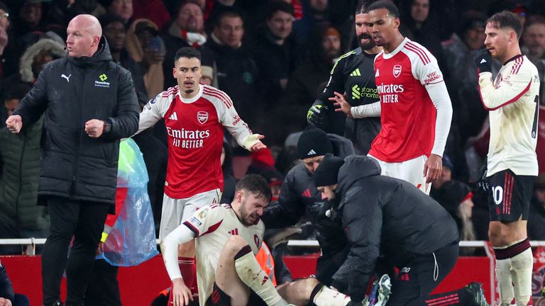 Conor Bradley of Liverpool is treated for injury as Gabriel Martinelli and Gabriel Magalhaes of Arsenal look on