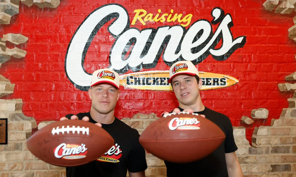 Christian and Luke McCaffrey holding footballs at Raising Cane's