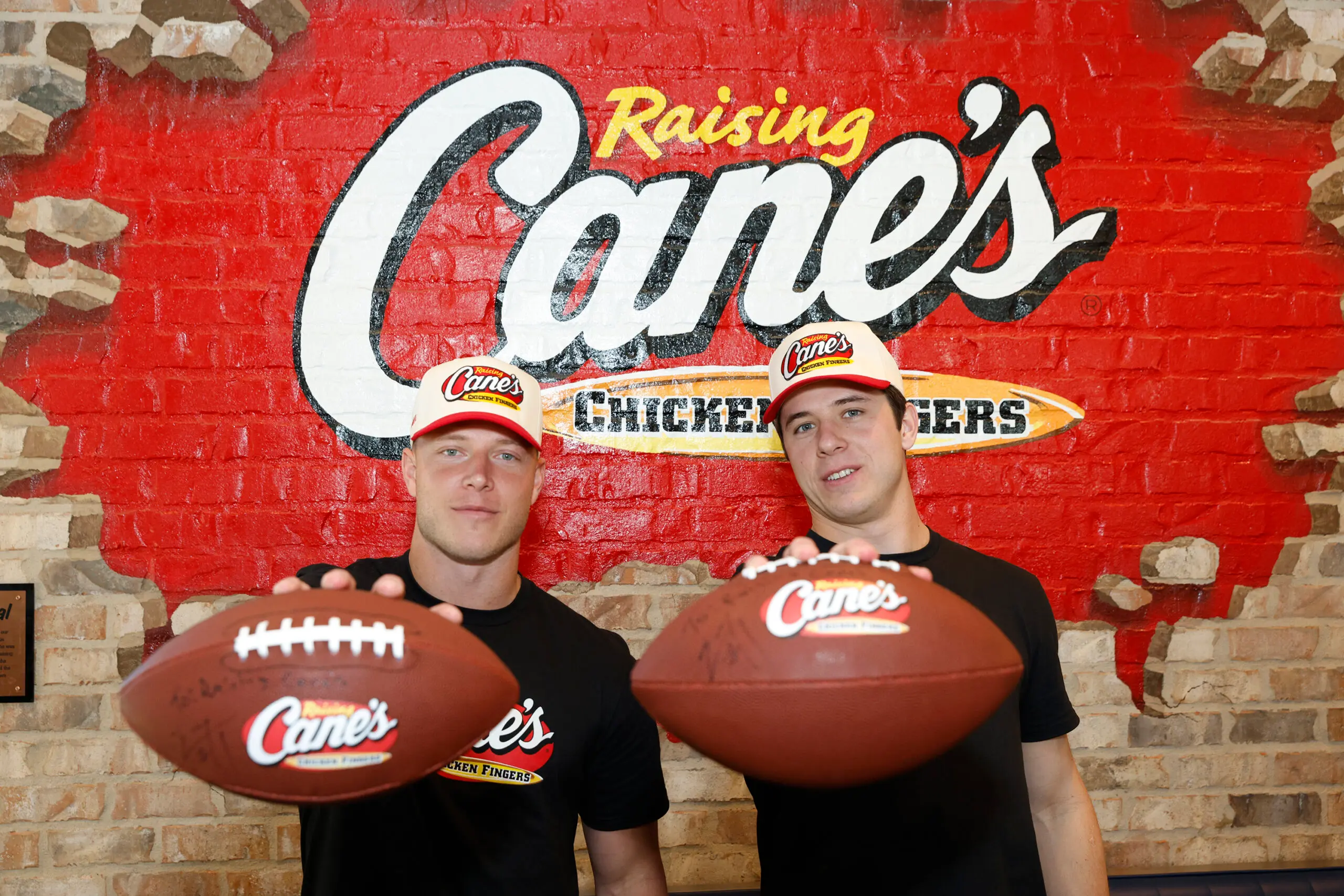 Christian and Luke McCaffrey holding footballs at Raising Cane's