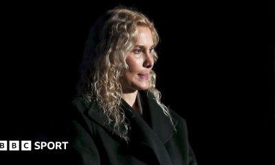 Blonde-haired coach Eteri Tutberidze in a black outfit against a black background
