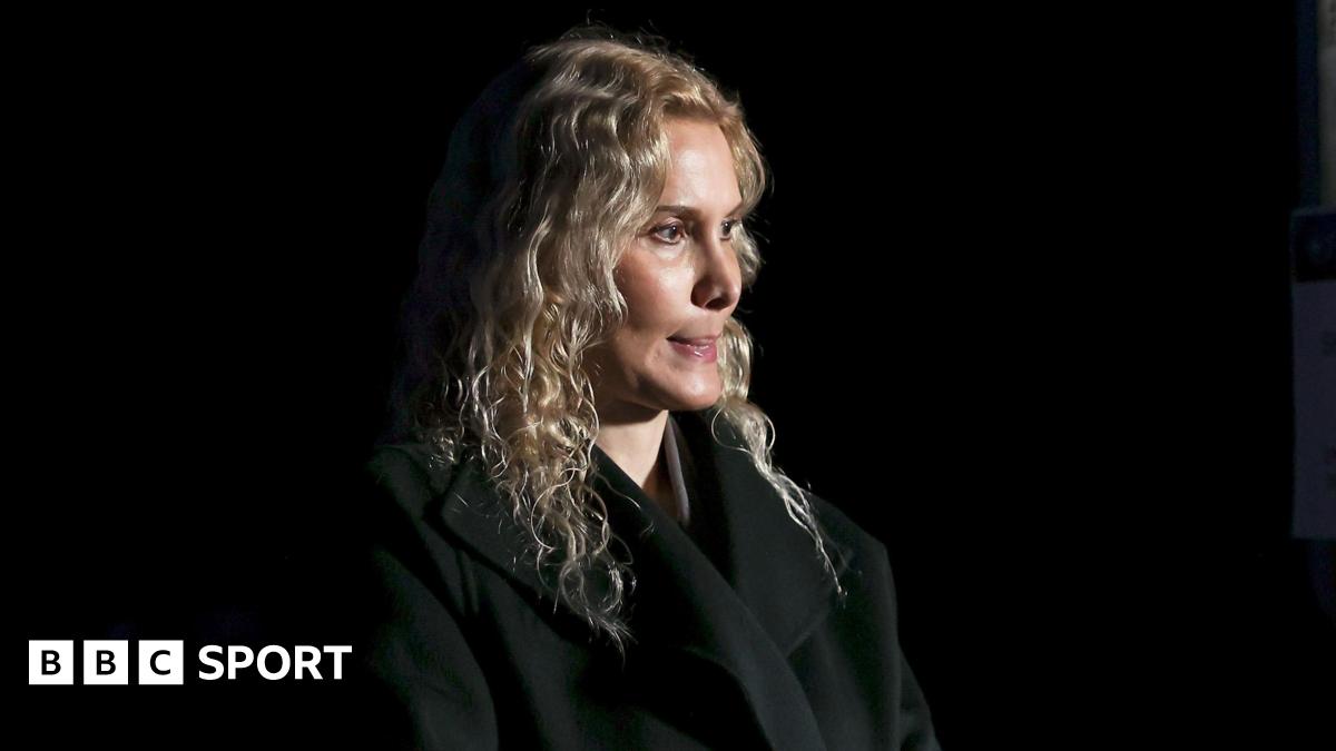 Blonde-haired coach Eteri Tutberidze in a black outfit against a black background