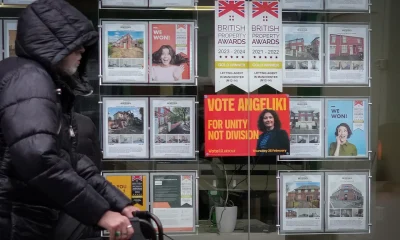 A man walks past a campaign poster for labour candidate Angeliki Stogia in an estate agents window in Longsight on February 11, 2026 in Manchester, United Kingdom.