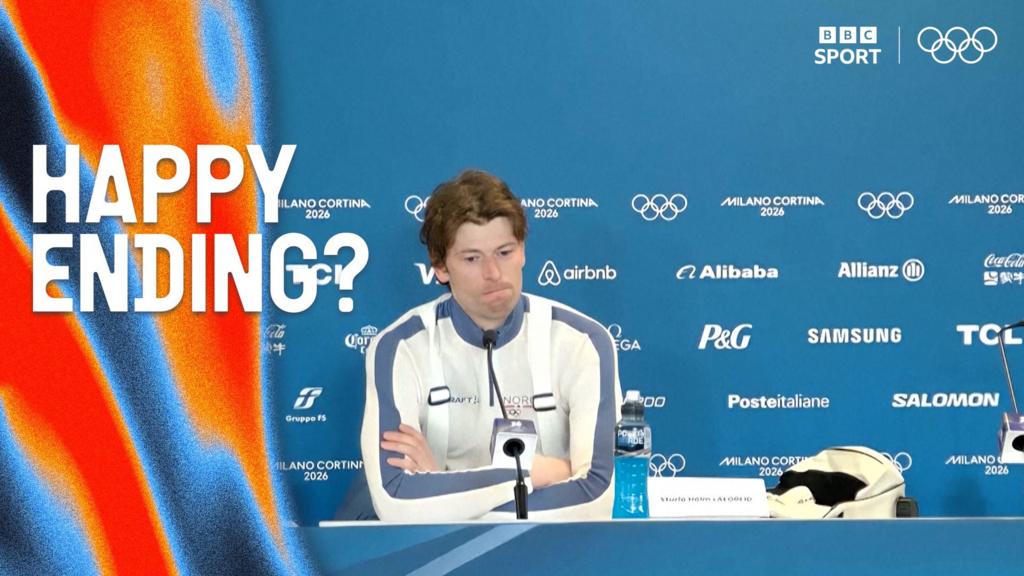 Sturla Holm Lægreid looks puzzled with his arms corssed in post biathlon presser